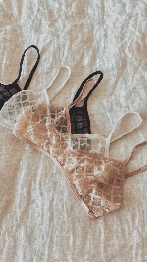 Mamoosh bralette's in white, black, and rose colors, resting on a linen sheet.